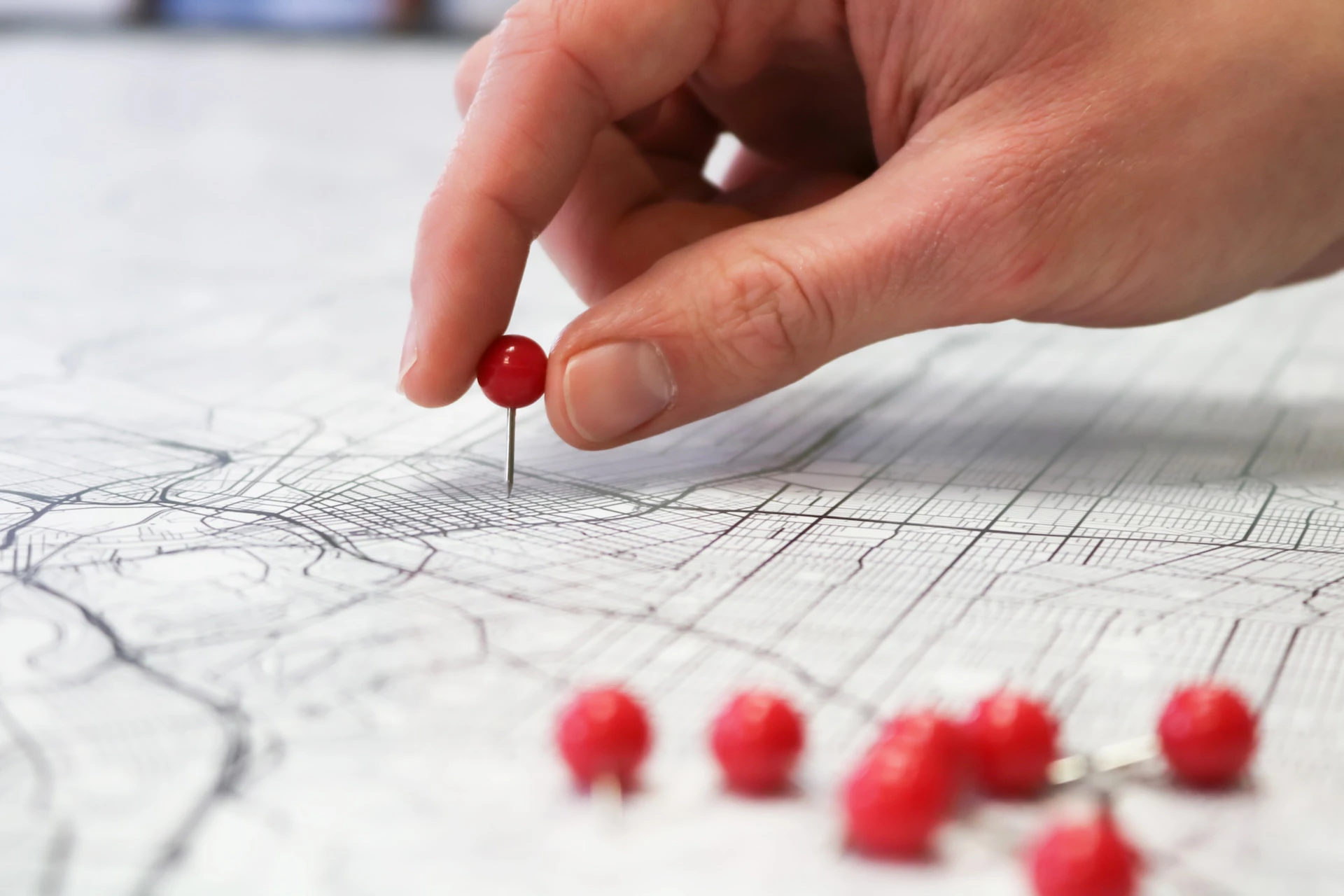 person's hand placing a red pin into a map