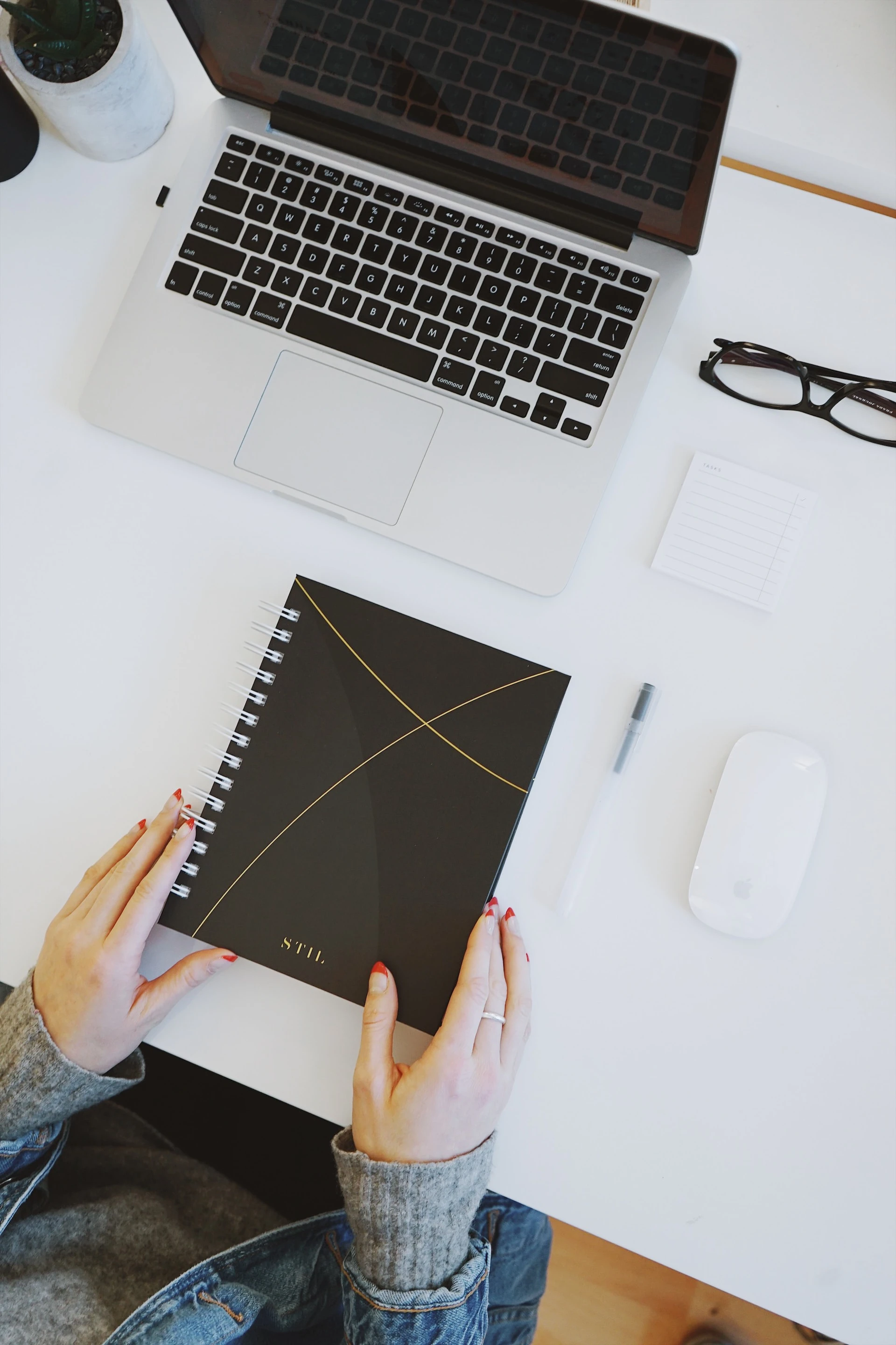 woman holding a black notebook on a white desk